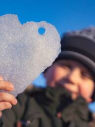 Poika näyttää lumisydäntä. En pojke håller fram ett hjärta av snö.